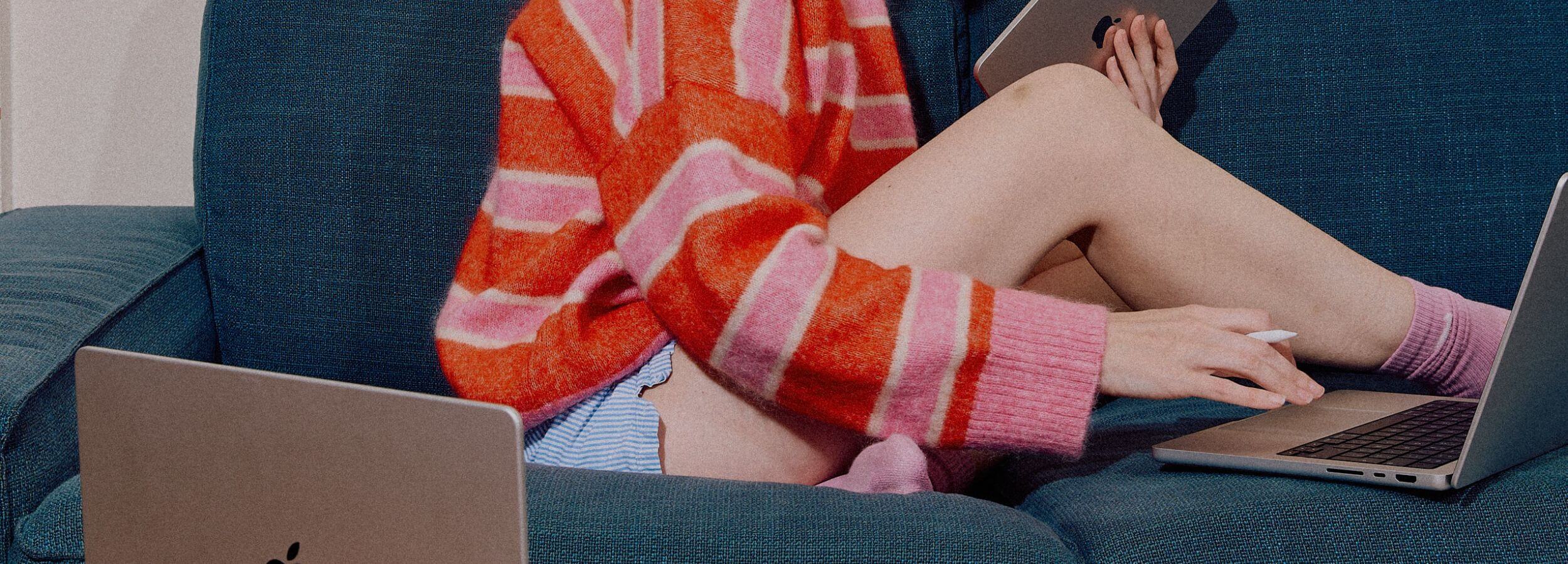 femme sur un canapé avec plusieurs ordinateurs et tablettes