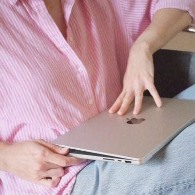 femme en chemise rose ouvrant un ordinateur portable pour écrire